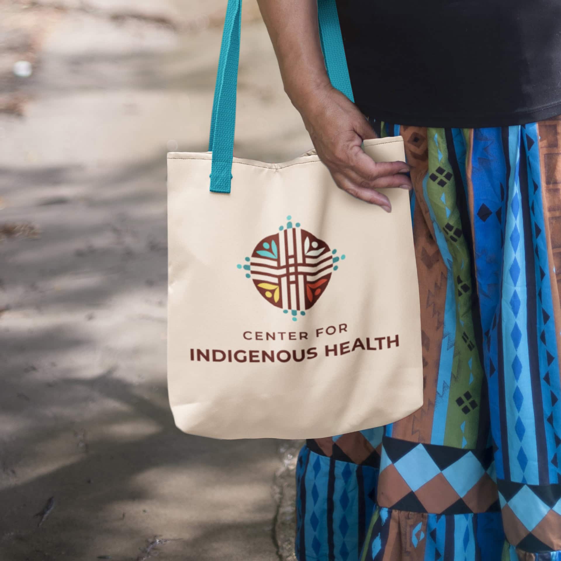 A woman carrying a bag which has the Center for Indigenous Health logo on it