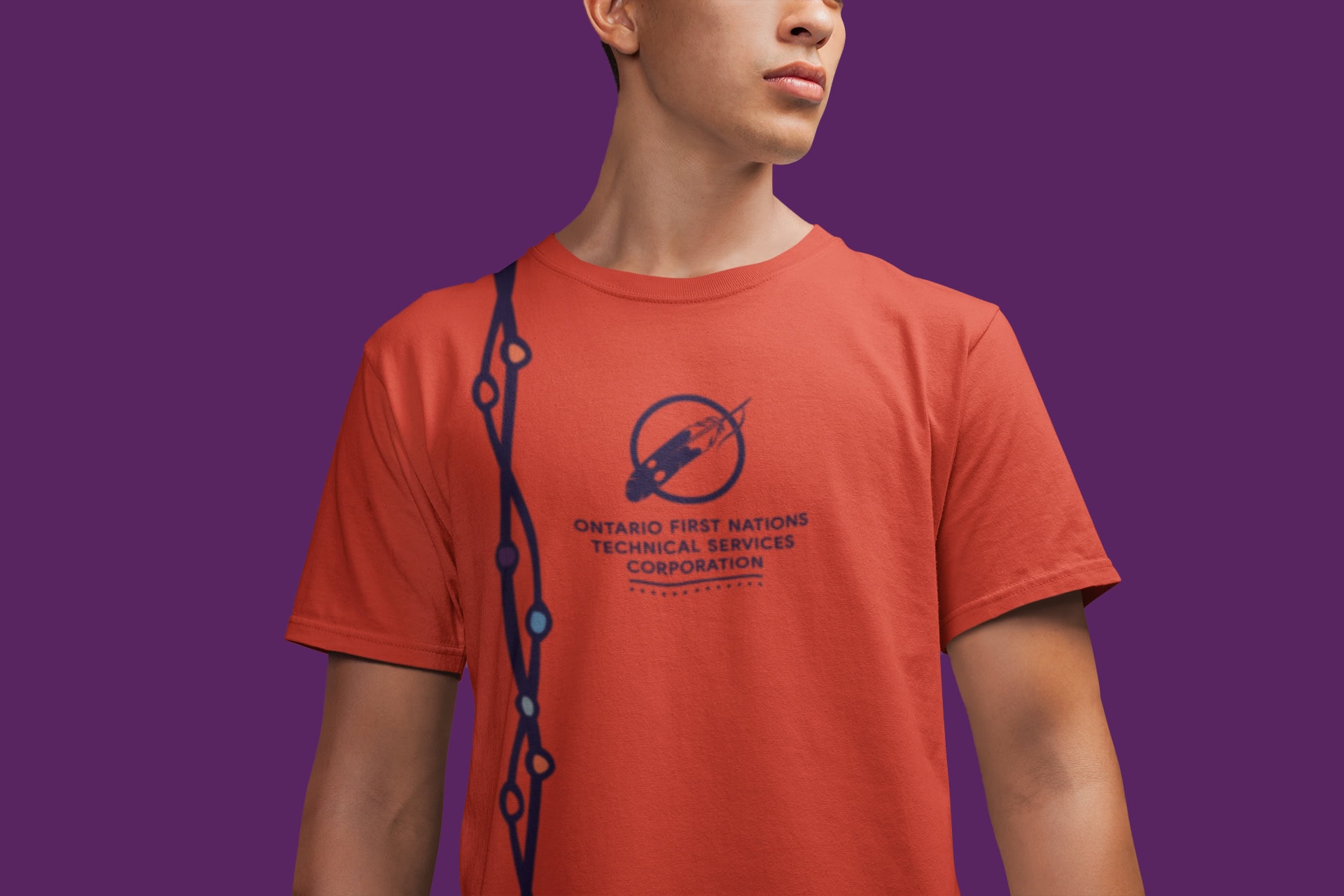 A person stands in front of a purple background with a bright orange shirt. On the shirt is the OFNTSC logo.