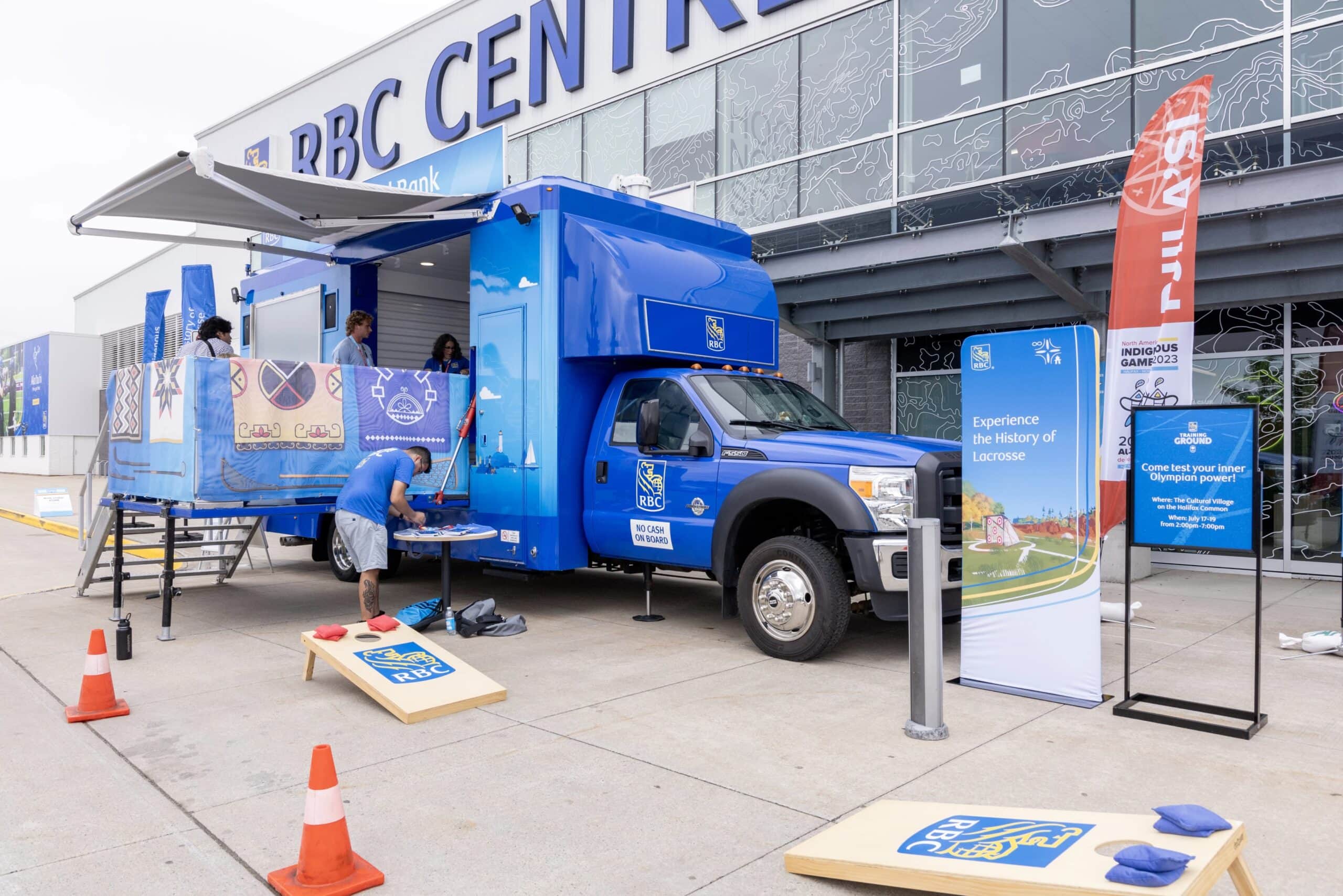 A large blue truck sits in front of RBC Centre. The sides of the truck have opened up to allow participants to view the History of Lacrosse VR experience in the interior.