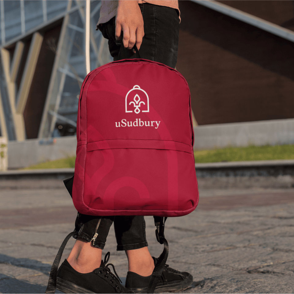 Student holding a red backpack with the uSudbury logo on it