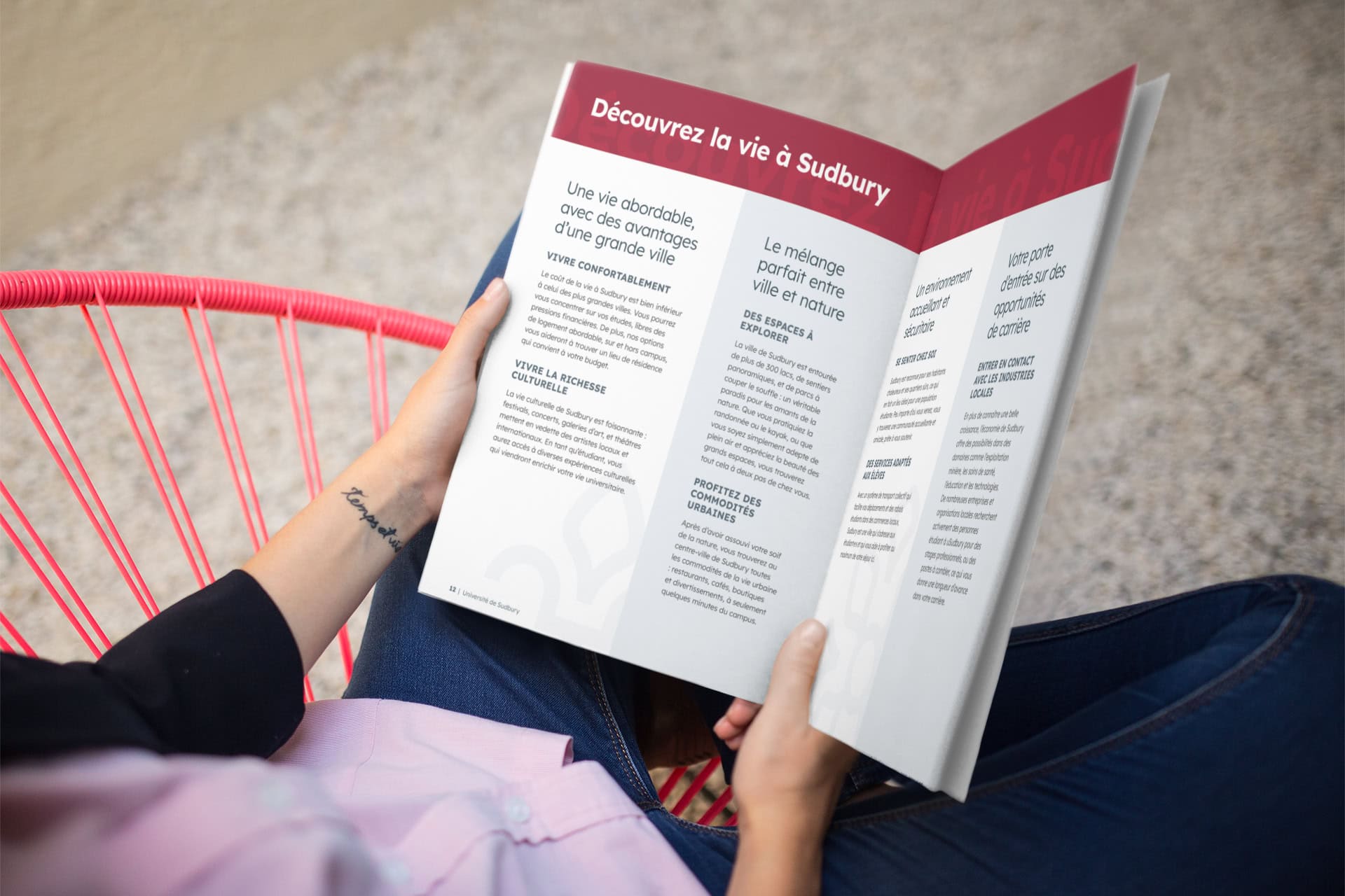 Student with a wrist tattoo reading the Université de Sudbury programme guide on a modern chair