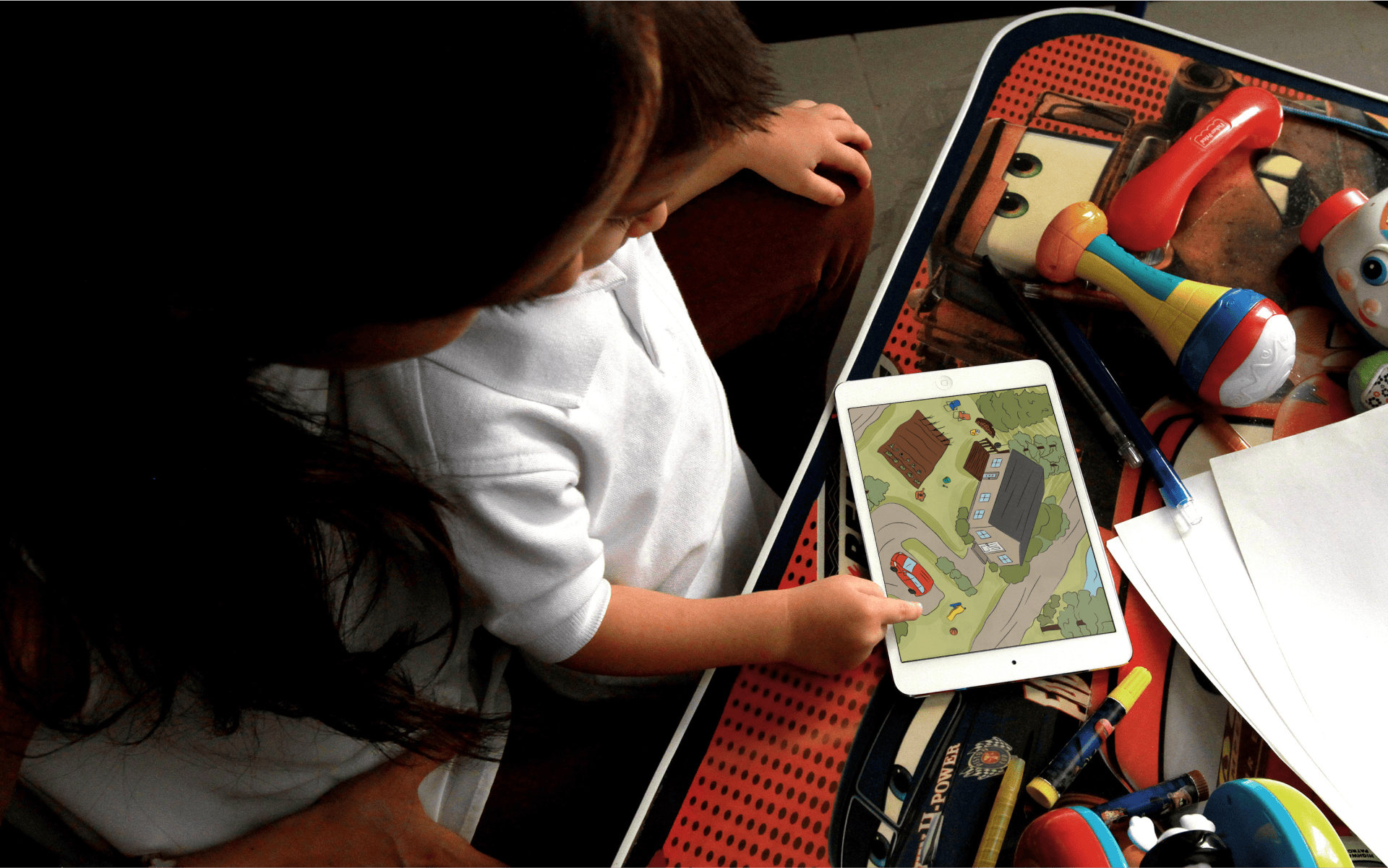 Toddler and his mother using a tablet with an illustration featuring a house and a garden.