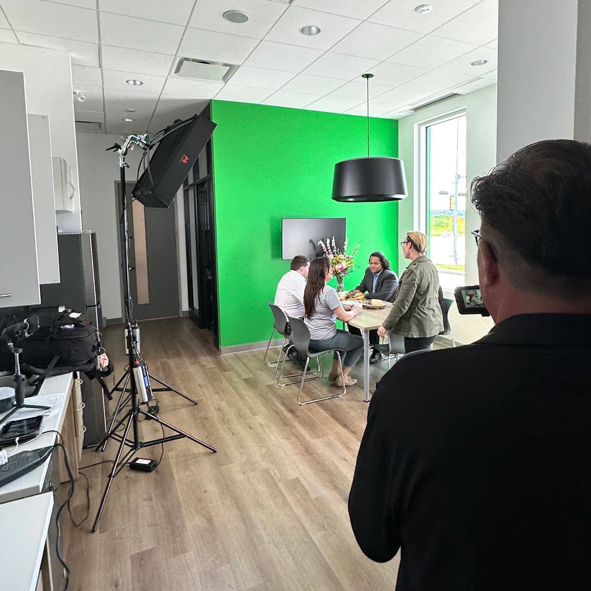 The DDP team filming a scene at a table in a bright space inside of TD Bank.